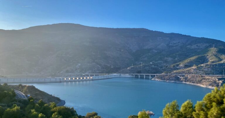 Vista del embalse de Rules, en el río Guadalfeo (Granada), con la presa al fondo entre laderas de monte bajo. El embalse será el depósito inferior de la central reversible de Los Guájares.